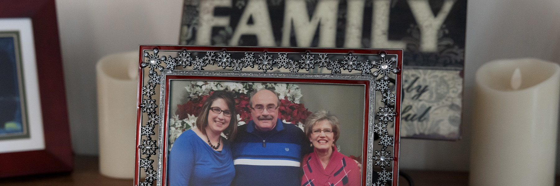 A frame containing a picture of an older couple with a younger woman. The frame is on a tabletop.