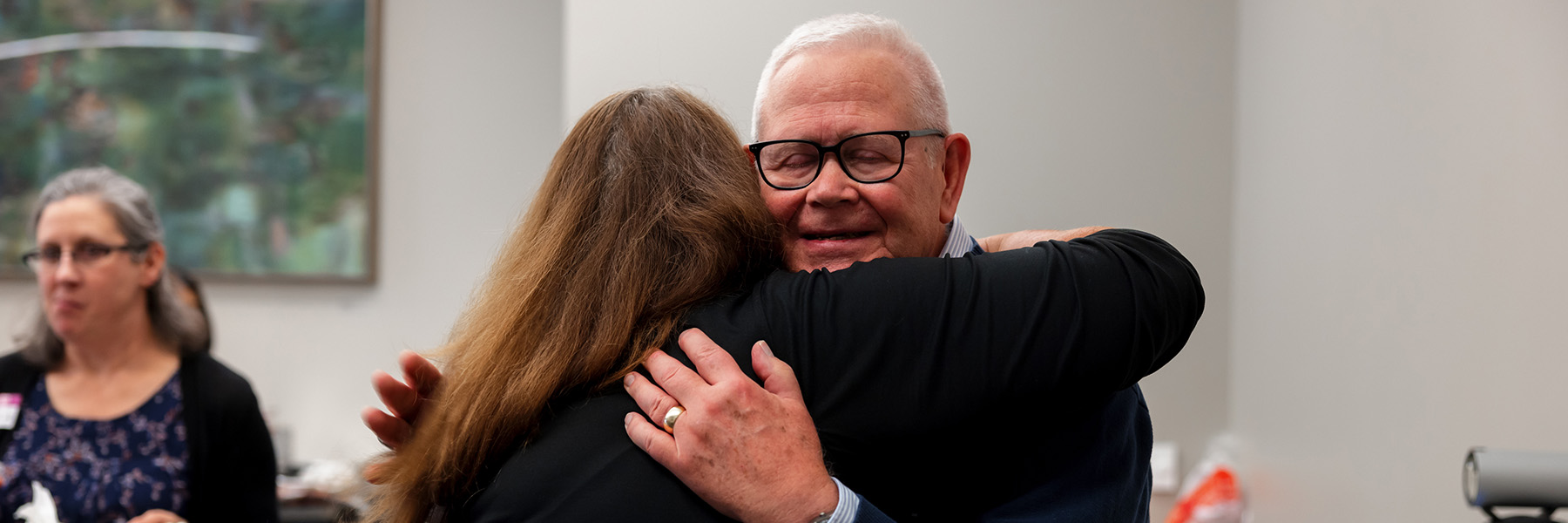 A man and a woman hug at an event.