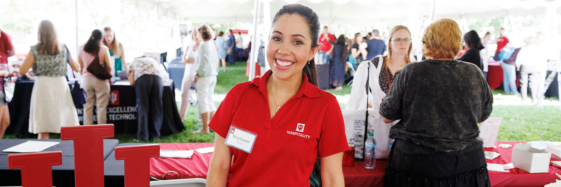 An IU Hospitality employee is working at a table at an outside campus event