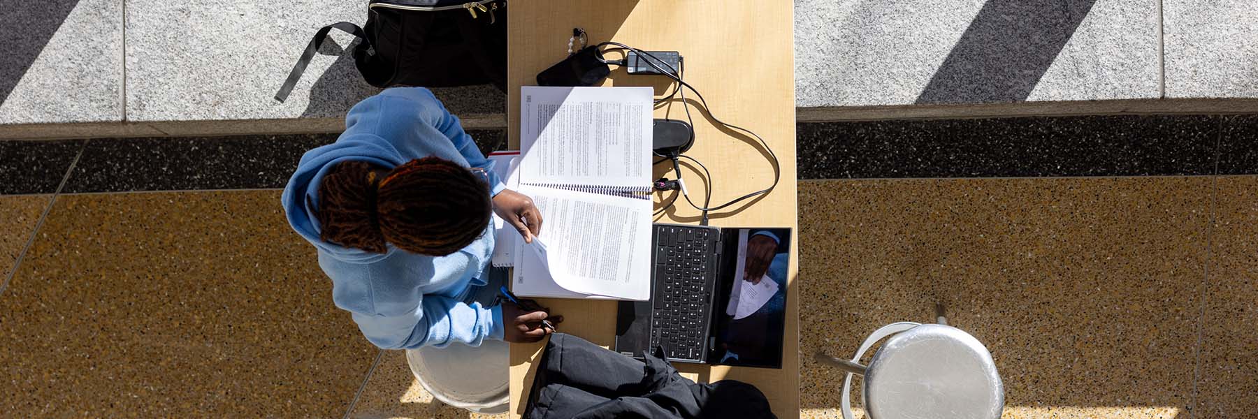 An overhead view of a person studying at a table.