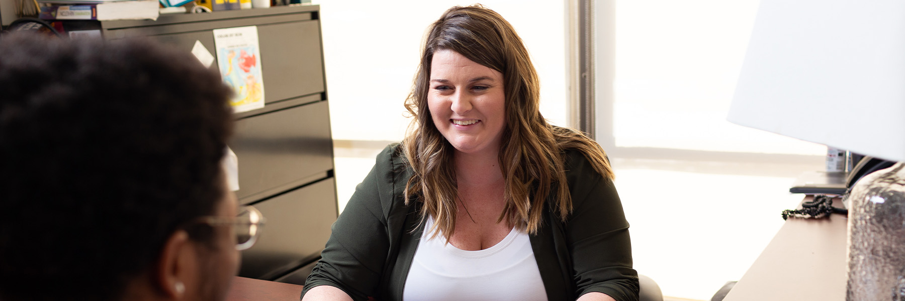 A woman sits behind a desk