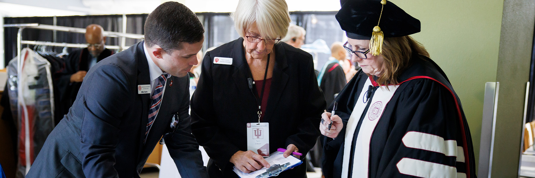 A professor and two events staff having a discussion at commencement