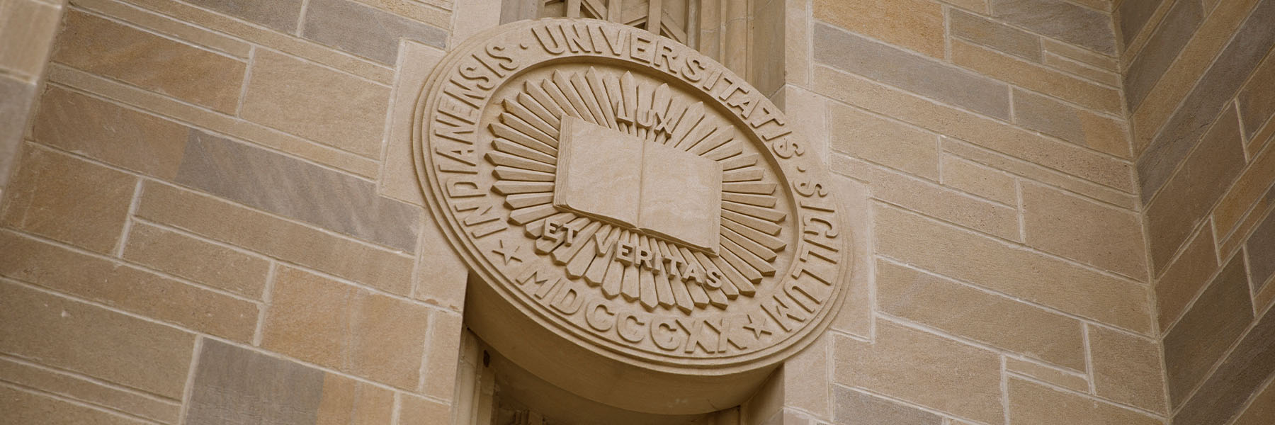 A limestone Indiana University Seal adorns the front of the Lilly Library on a summer day at IU Bloomington